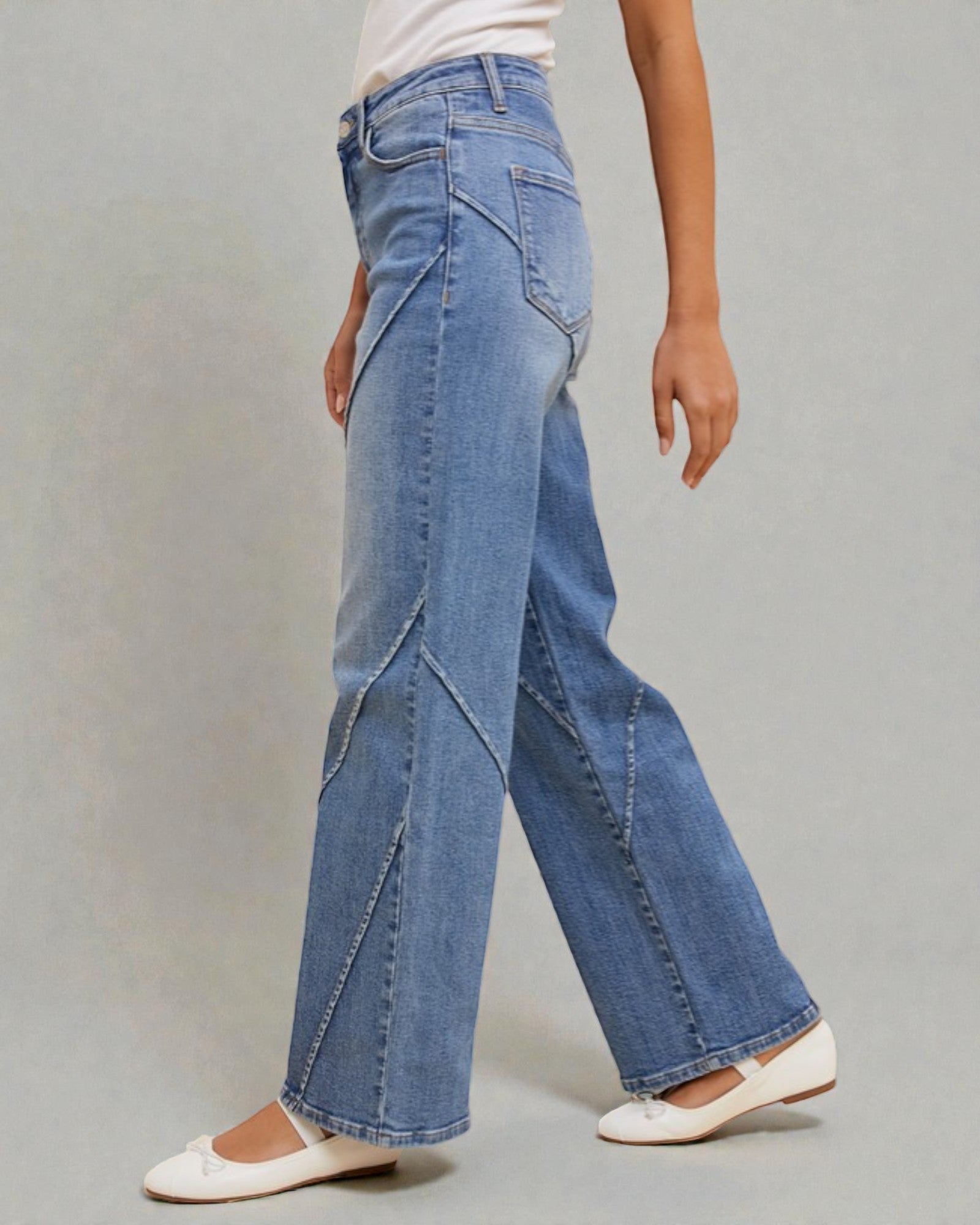 Person wearing blue wide-leg jeans on a gray background