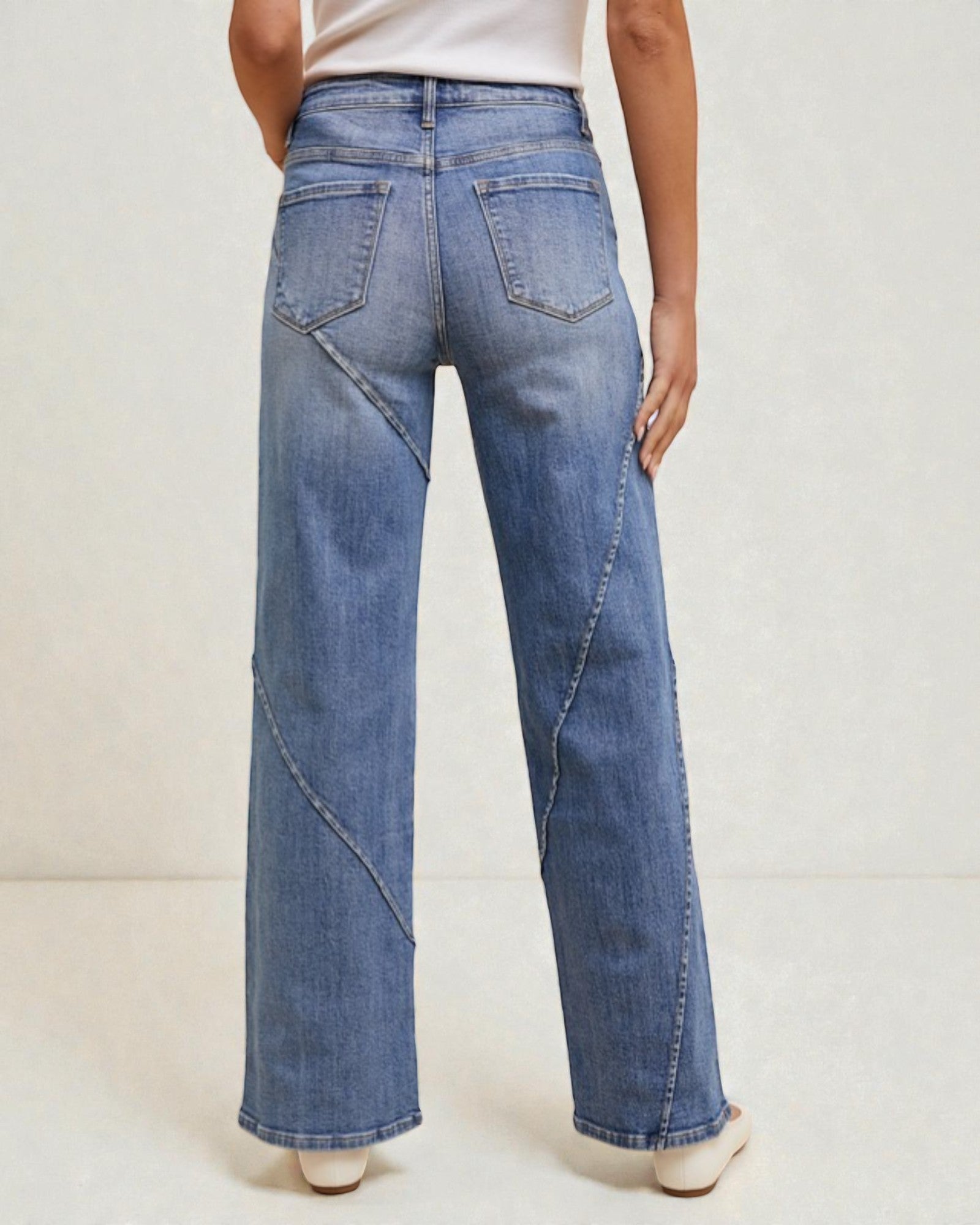 Person wearing blue wide-leg jeans on a plain background