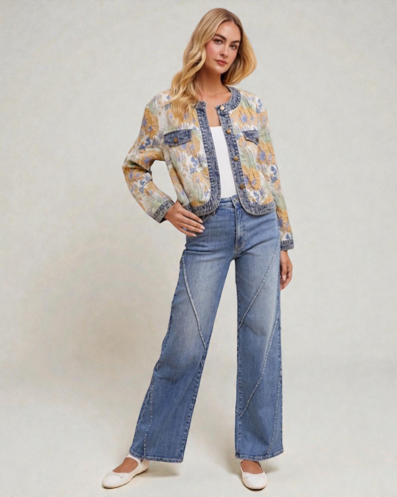 Woman wearing a floral jacket and blue jeans on a plain background