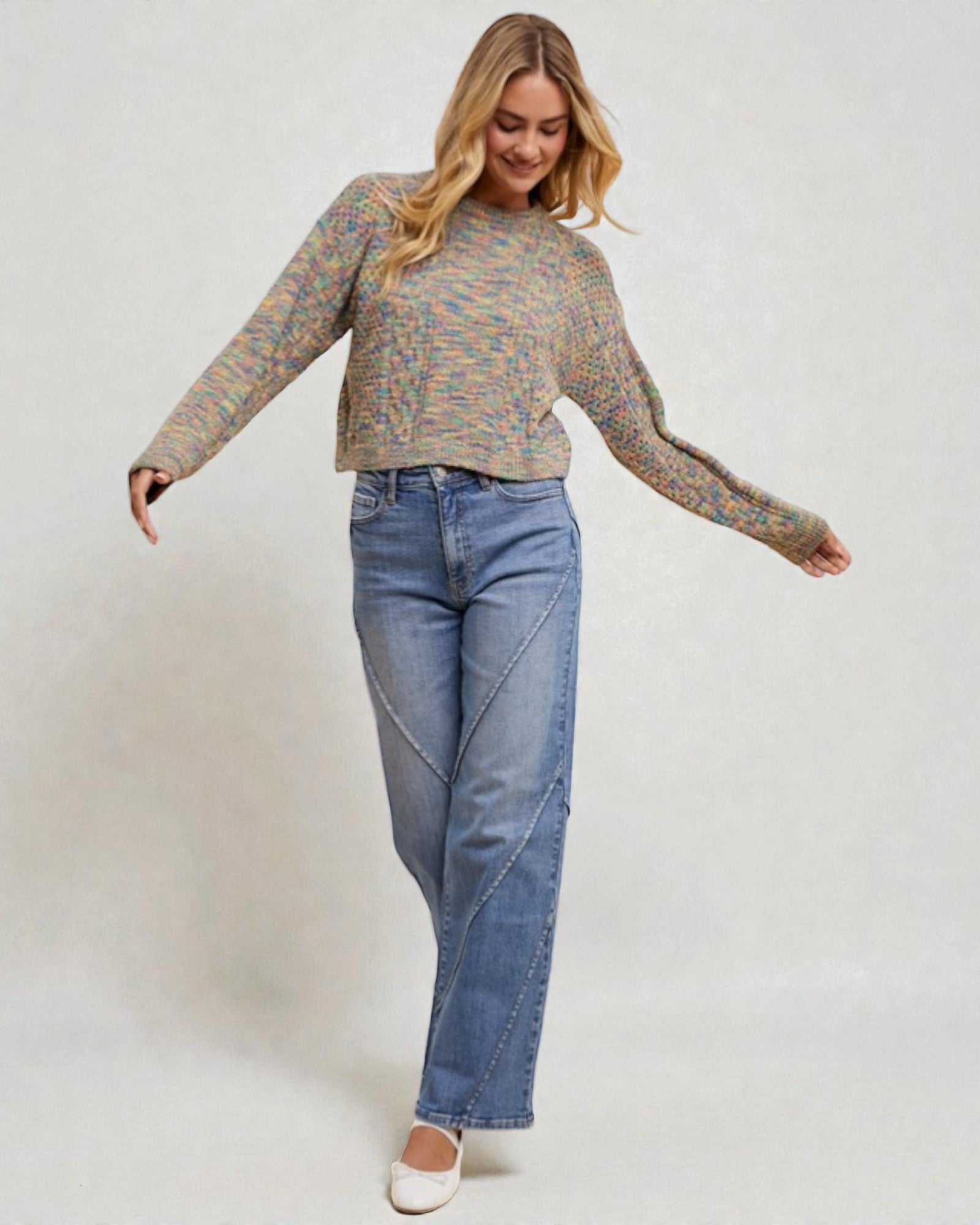Woman wearing a patterned sweater and blue jeans on a plain background