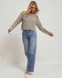 Woman wearing a patterned sweater and blue jeans on a plain background