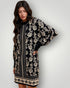 Woman wearing a black and white floral patterned dress against a plain background
