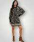Woman wearing a black and white patterned dress with brown boots on a white background