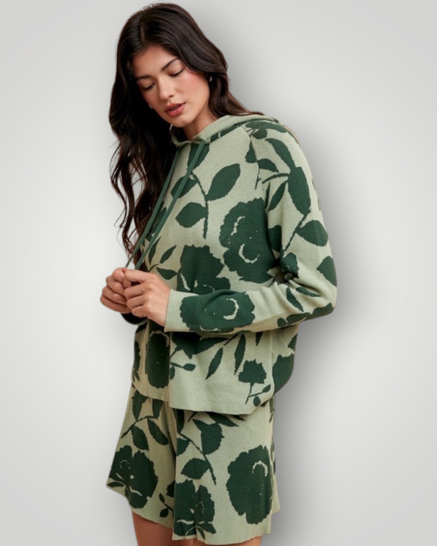 Woman wearing a green floral patterned outfit on a plain background