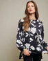 Woman wearing a black floral blouse against a neutral background