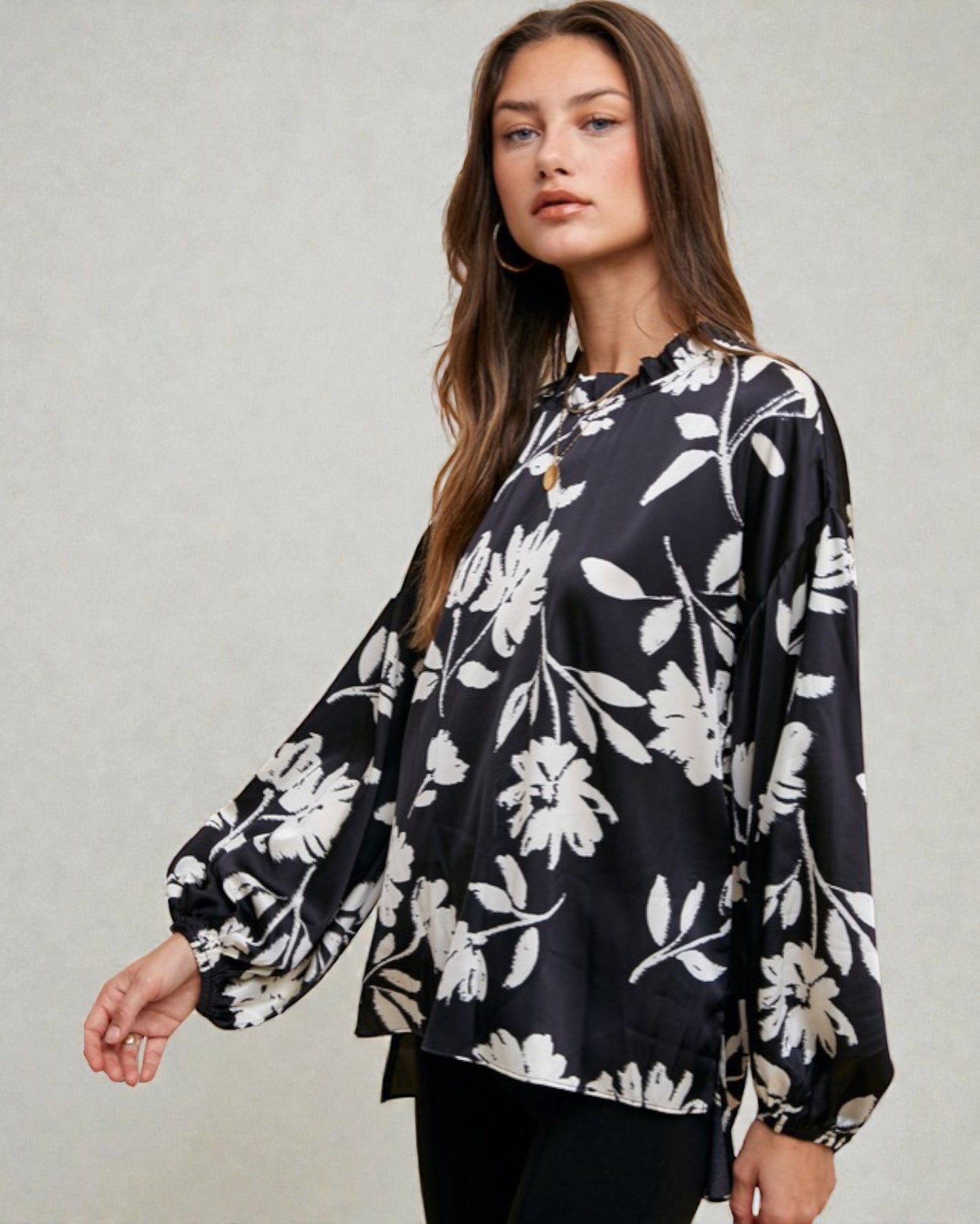 Woman wearing a black floral blouse against a plain background