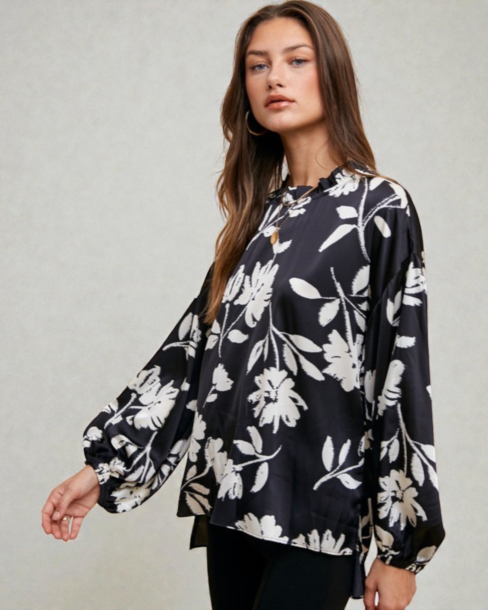 Woman wearing a black floral blouse against a plain background