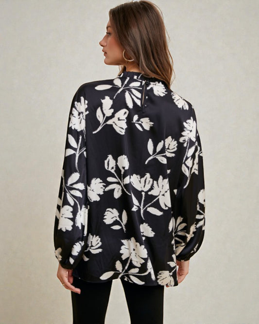 Woman wearing a black floral blouse against a plain background