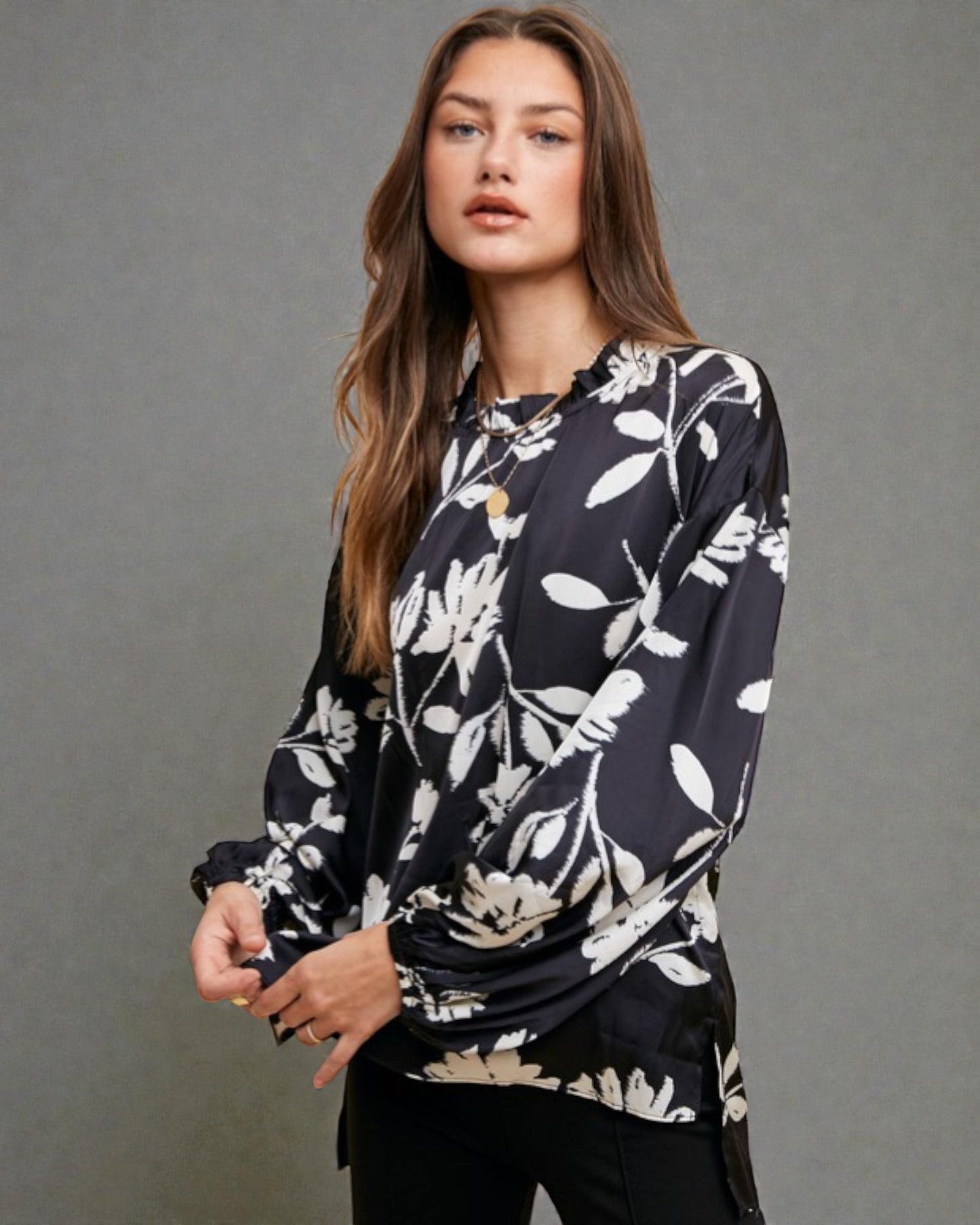 Woman wearing a black floral blouse against a gray background
