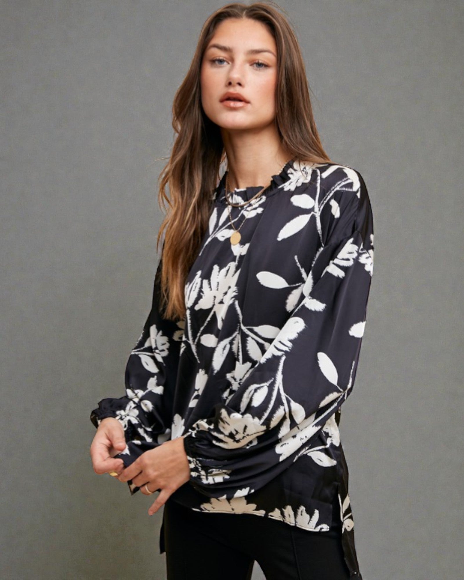 Woman wearing a black floral blouse against a gray background