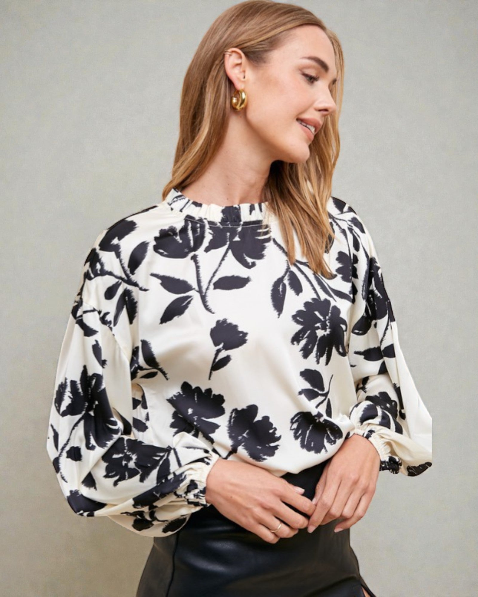Woman wearing a white blouse with black floral pattern against a gray background