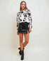 Woman wearing a floral blouse and black leather skirt on a white background