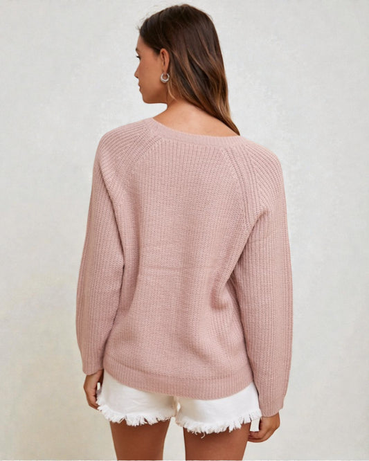 Woman wearing a pink sweater and white shorts on a plain background