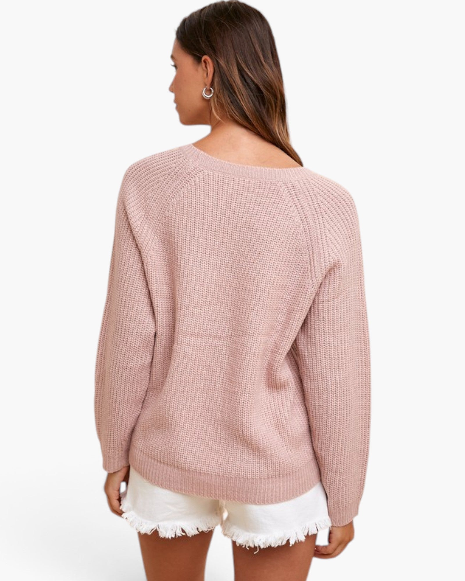 A woman shown from the back wearing a dusty pink ribbed knit sweater and white frayed denim shorts against a plain white studio background.