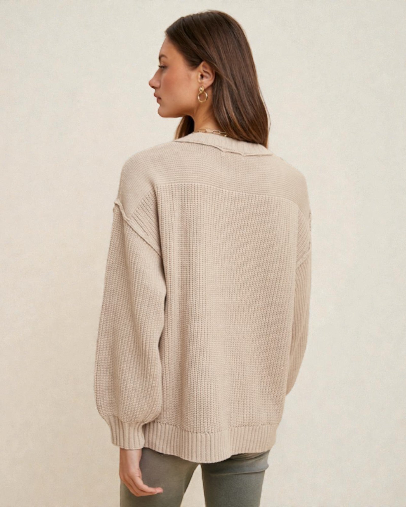 Woman wearing a beige knitted cardigan on a plain background