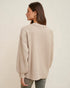 Woman wearing a beige knitted cardigan on a plain background