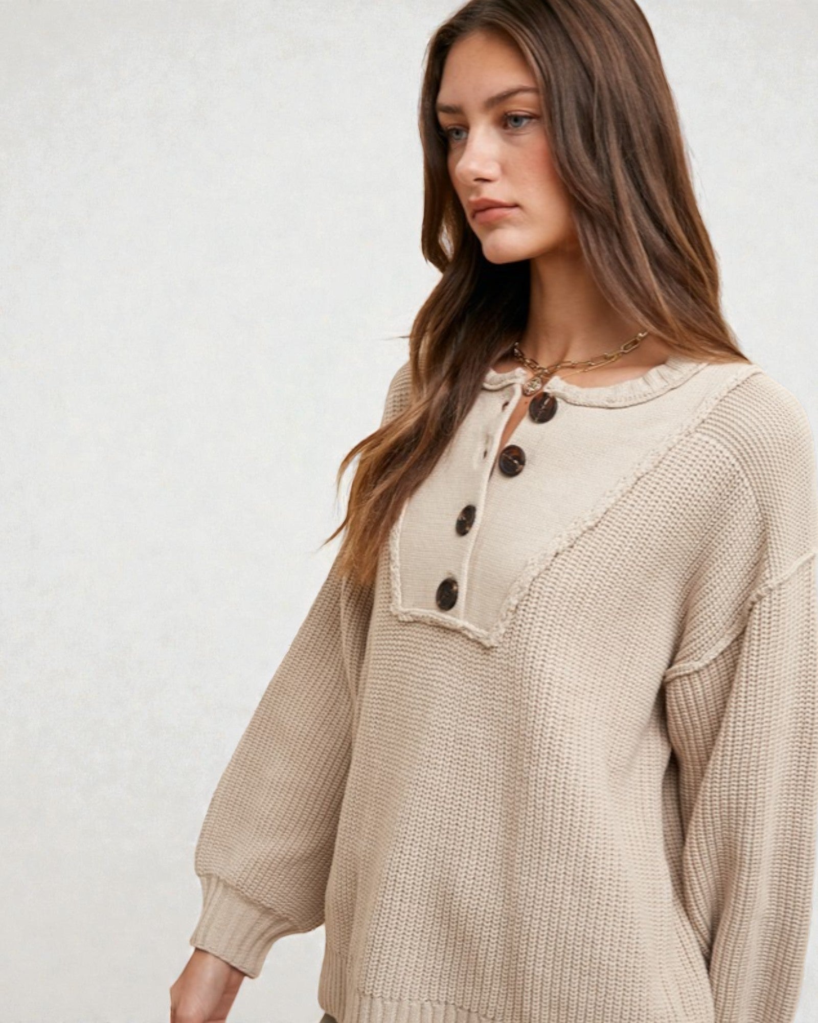 Woman wearing a beige textured blouse with black buttons on a white background