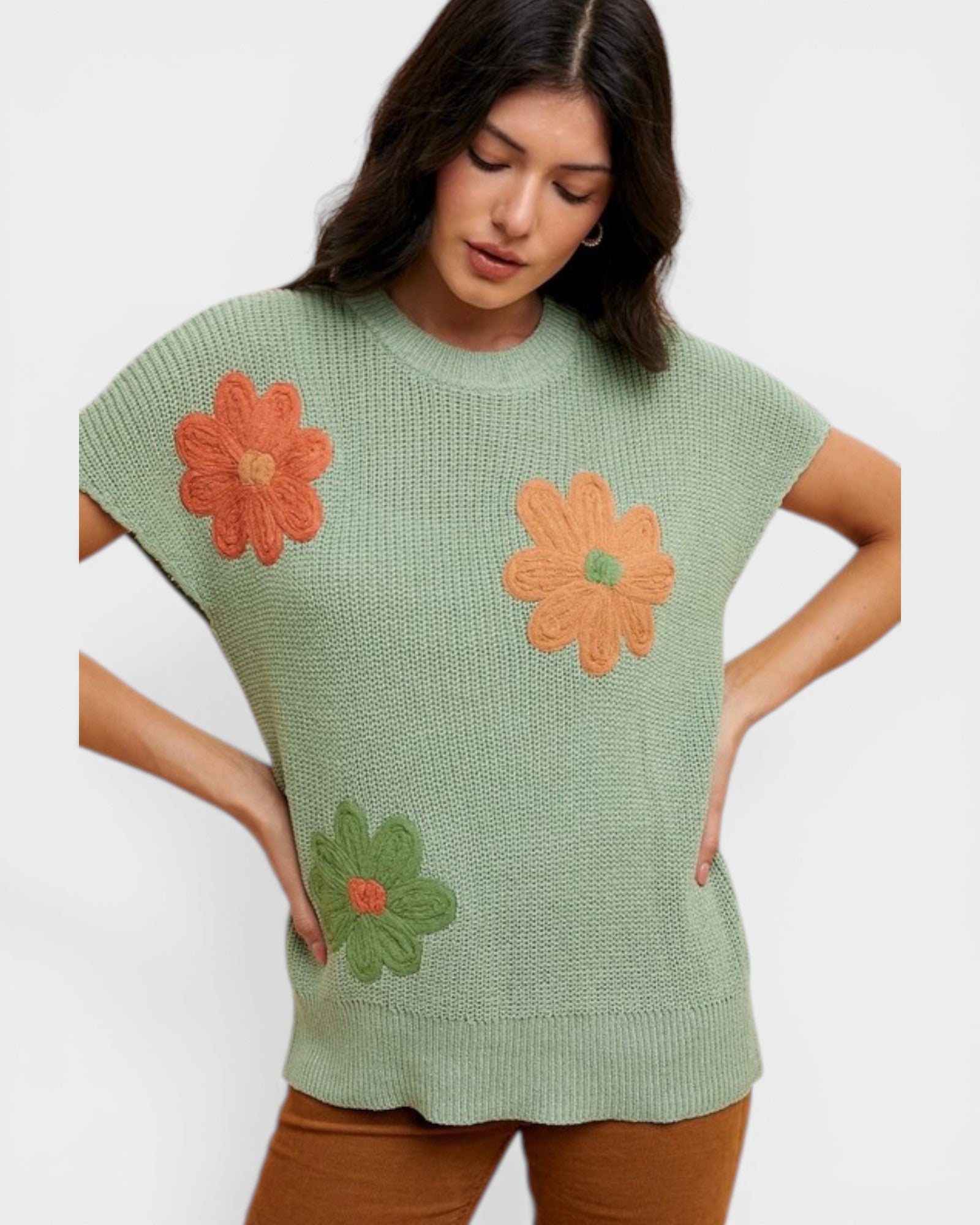 Woman wearing a green knitted top with orange flowers on a white background