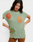 Woman wearing a green knitted top with orange flowers on a white background