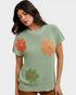 Woman wearing a green sweater with orange and green floral patterns on a white background