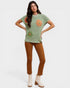 Woman wearing a green sweater with floral patterns and brown pants on a white background