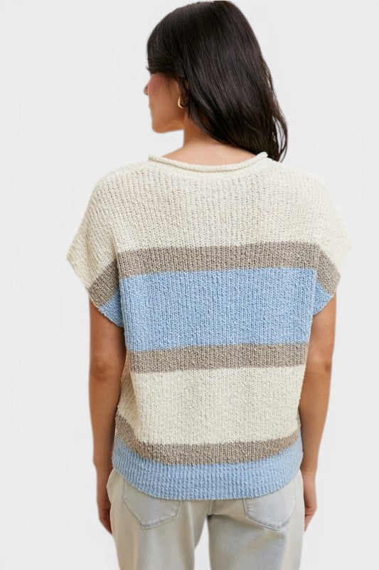 Woman wearing a striped sweater with a neutral and blue color scheme on a white background
