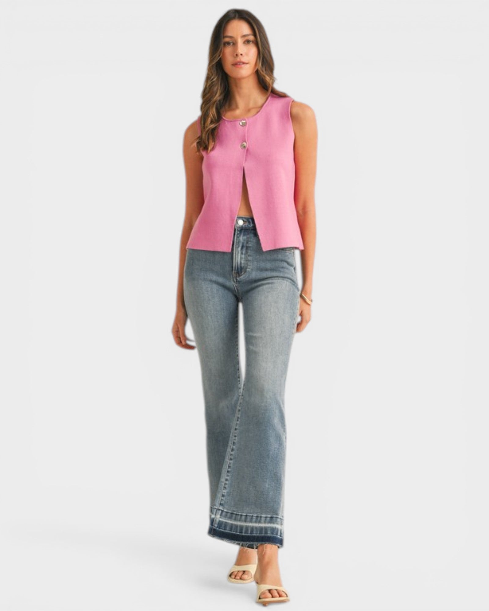 Woman wearing a pink sleeveless top and blue jeans on a white background