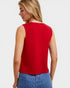 Woman wearing a red sleeveless top and blue jeans on a light gray background