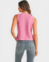 Woman wearing a pink sleeveless top and blue jeans on a white background