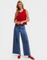 Woman wearing a red sleeveless top and blue jeans on a white background