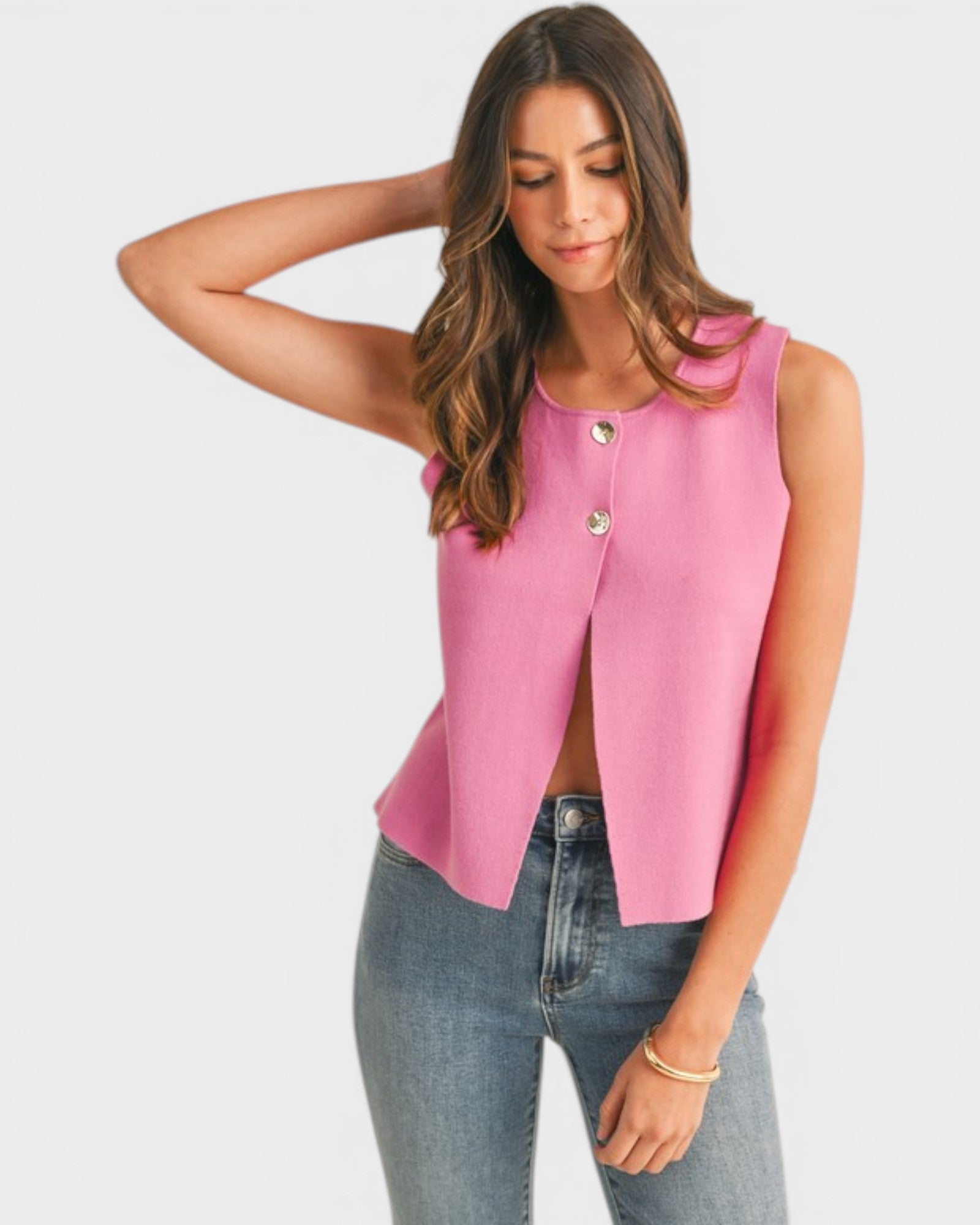 Woman wearing a pink sleeveless top with buttons and blue jeans on a white background