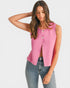 Woman wearing a pink sleeveless top with buttons and blue jeans on a white background