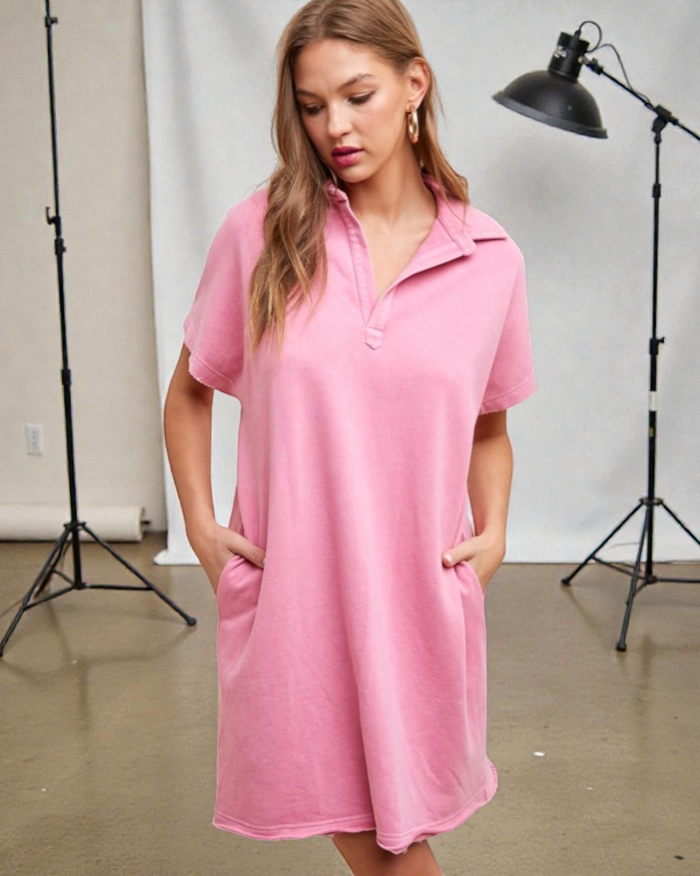 Woman wearing a pink dress in a studio setting with photography equipment.