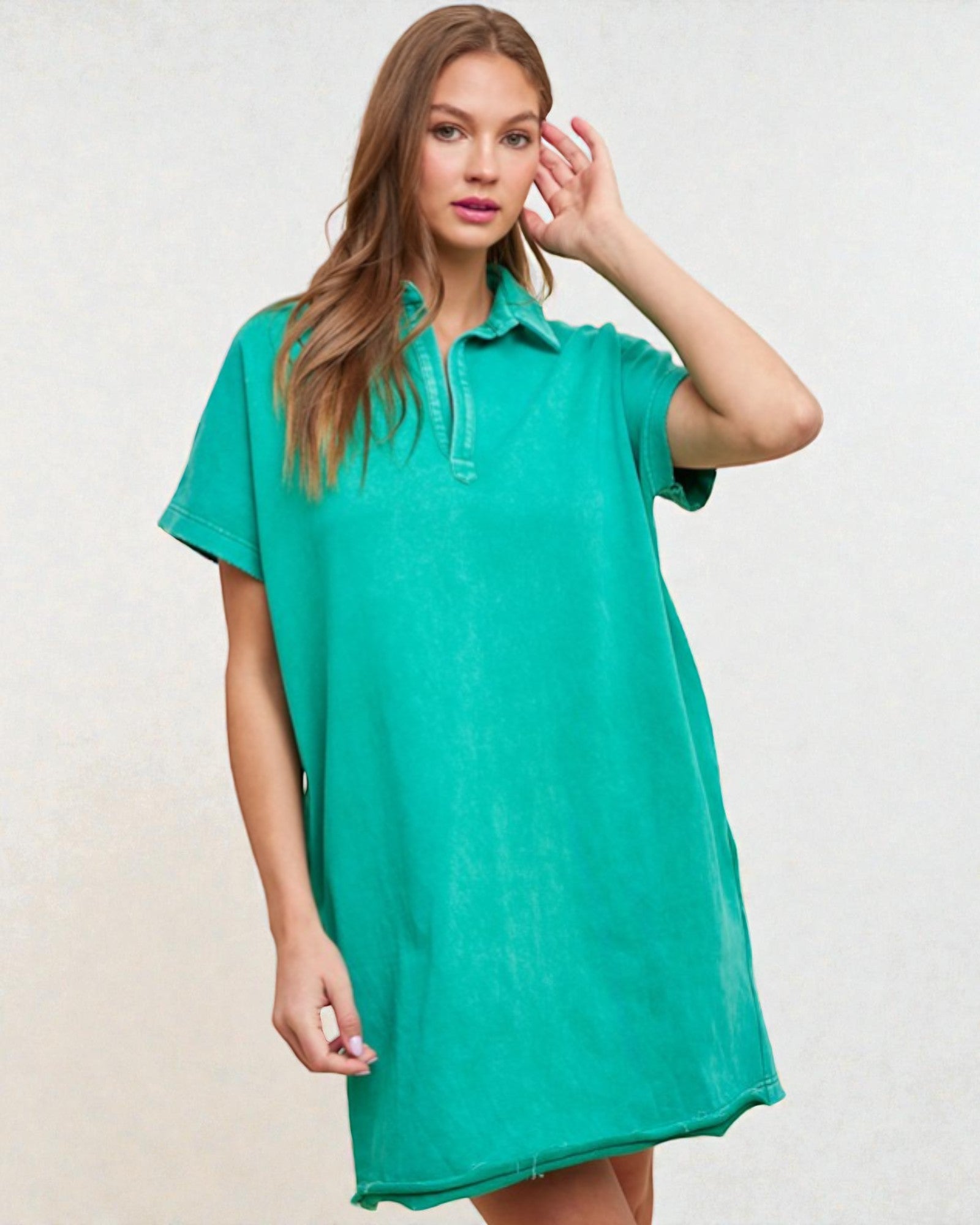 Woman wearing a teal dress against a plain background