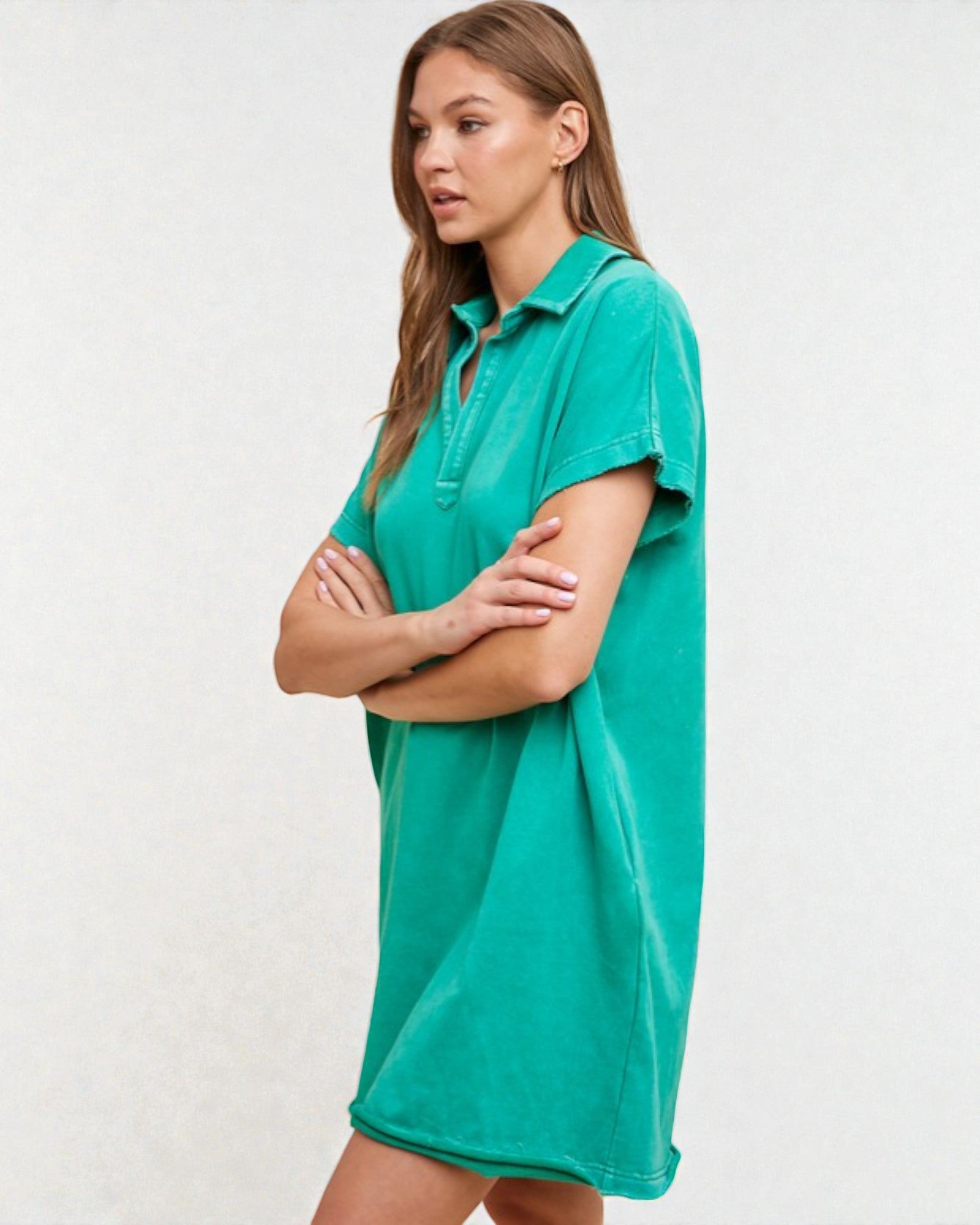 Woman wearing a teal polo shirt dress against a white background