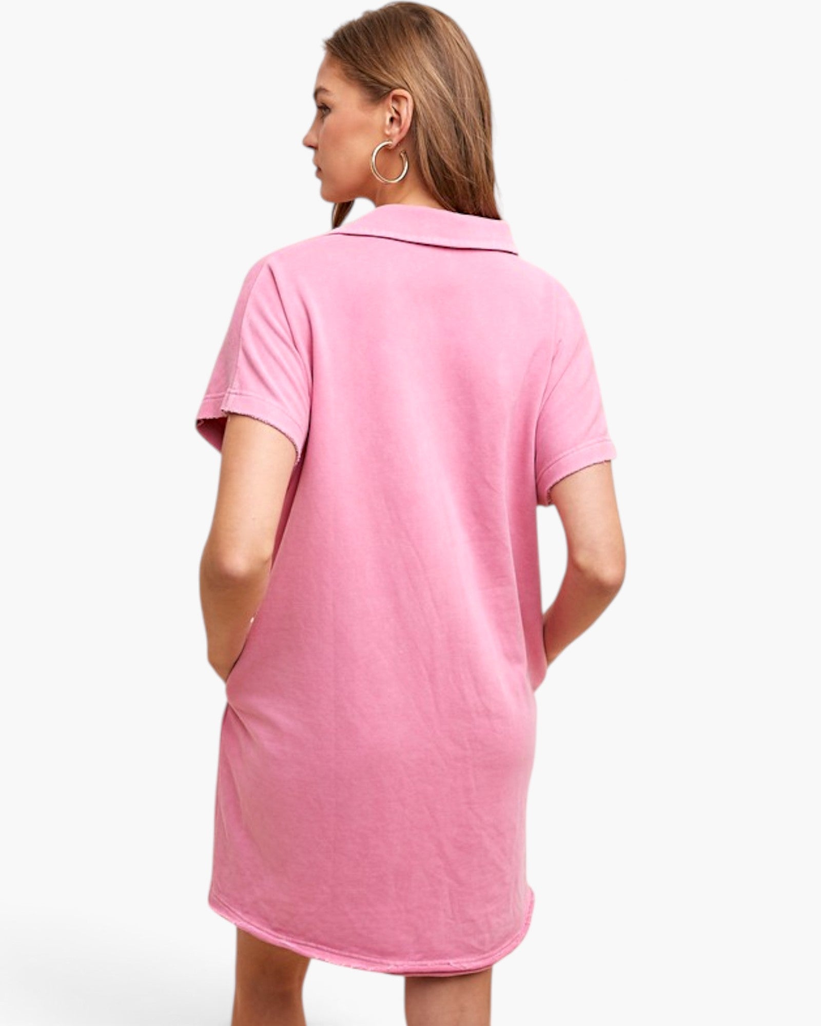 A woman shown from the back wearing a pink short-sleeve polo shirt dress against a plain white studio background.