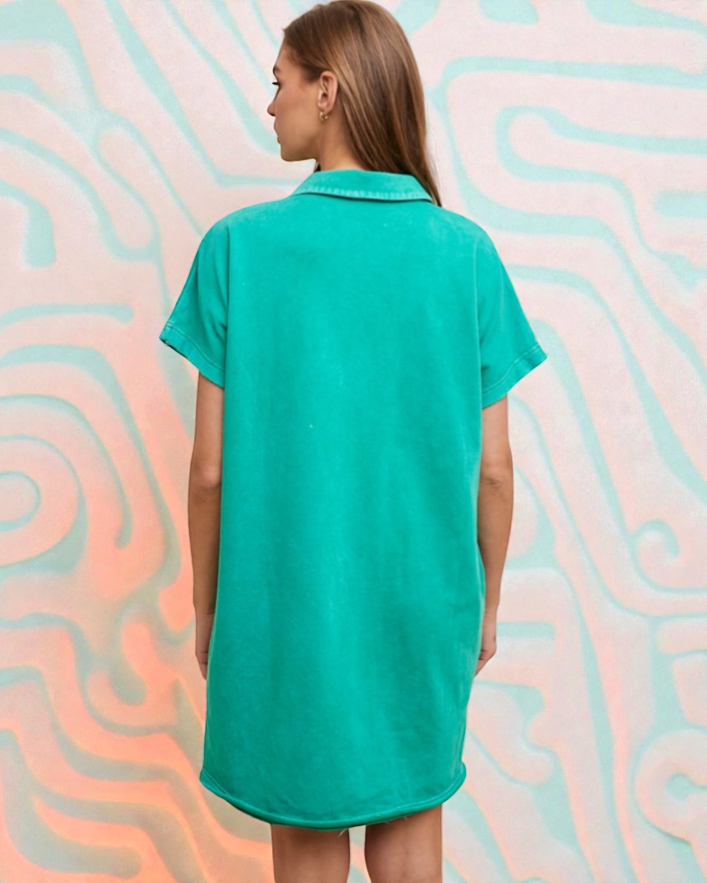 Person wearing a teal dress against a colorful, abstract background