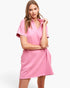 A woman modeling a pink short-sleeve polo shirt dress against a clean white background.