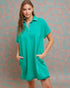 Woman wearing a teal dress against a patterned wall