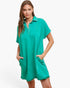A woman modeling a short-sleeve, collared, polo-style nightshirt in a vibrant teal green color, set against a plain white studio background.