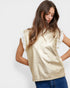 Woman wearing a gold top with ruffled sleeves on a white background