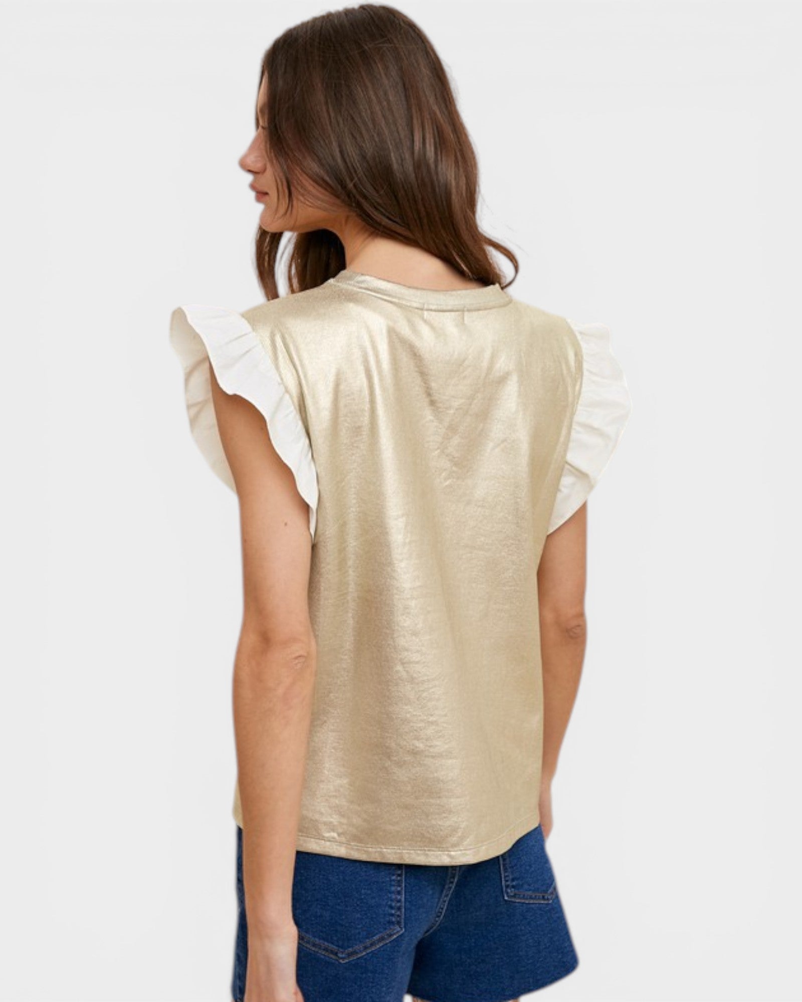 Woman wearing a gold sleeveless top with white sleeves on a plain background