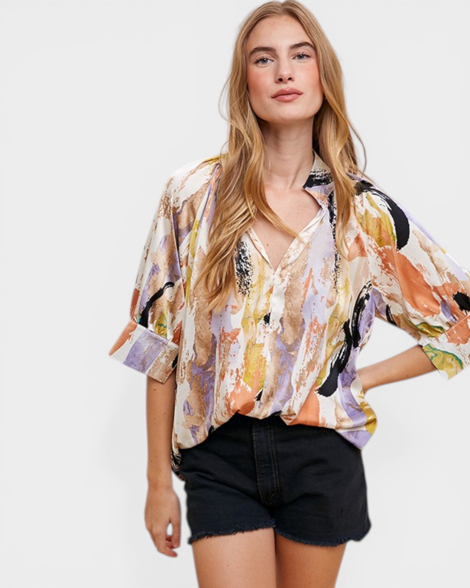 Woman wearing a colorful patterned shirt and black shorts on a white background