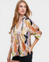 Woman wearing a colorful floral blouse against a plain background