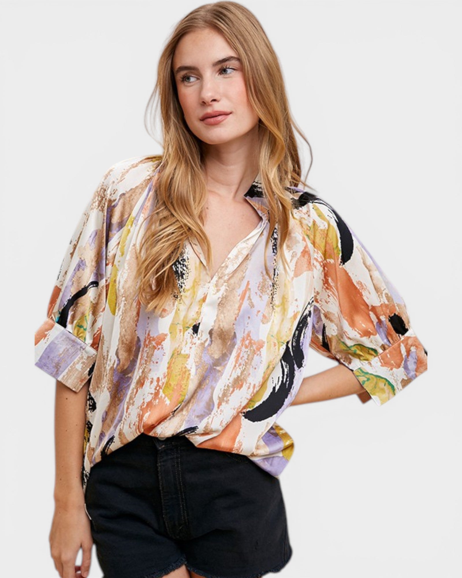 Woman wearing a colorful floral blouse with black shorts on a white background