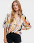 Woman wearing a colorful floral blouse with black shorts on a white background