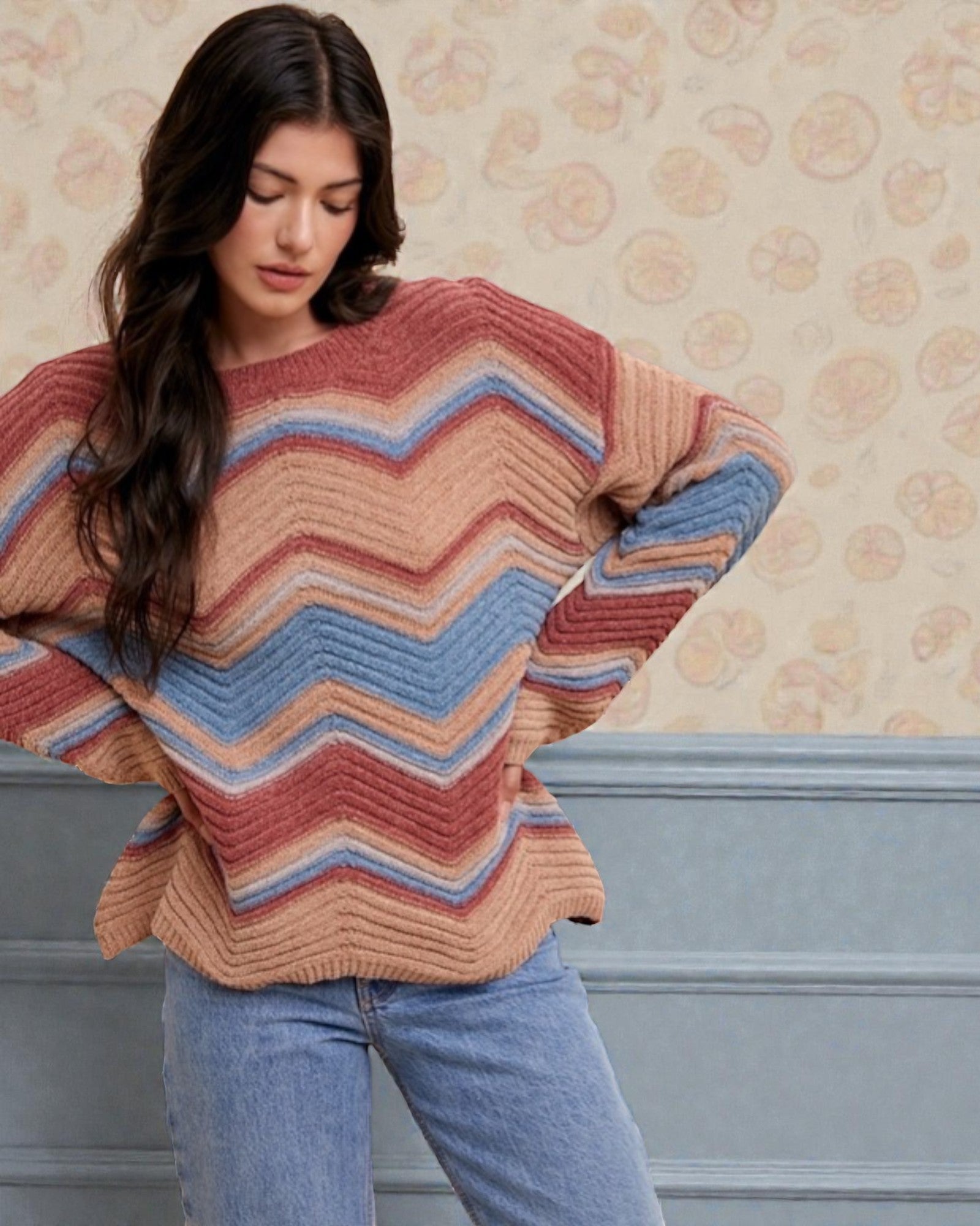 Woman wearing a colorful striped sweater against a floral wallpaper background