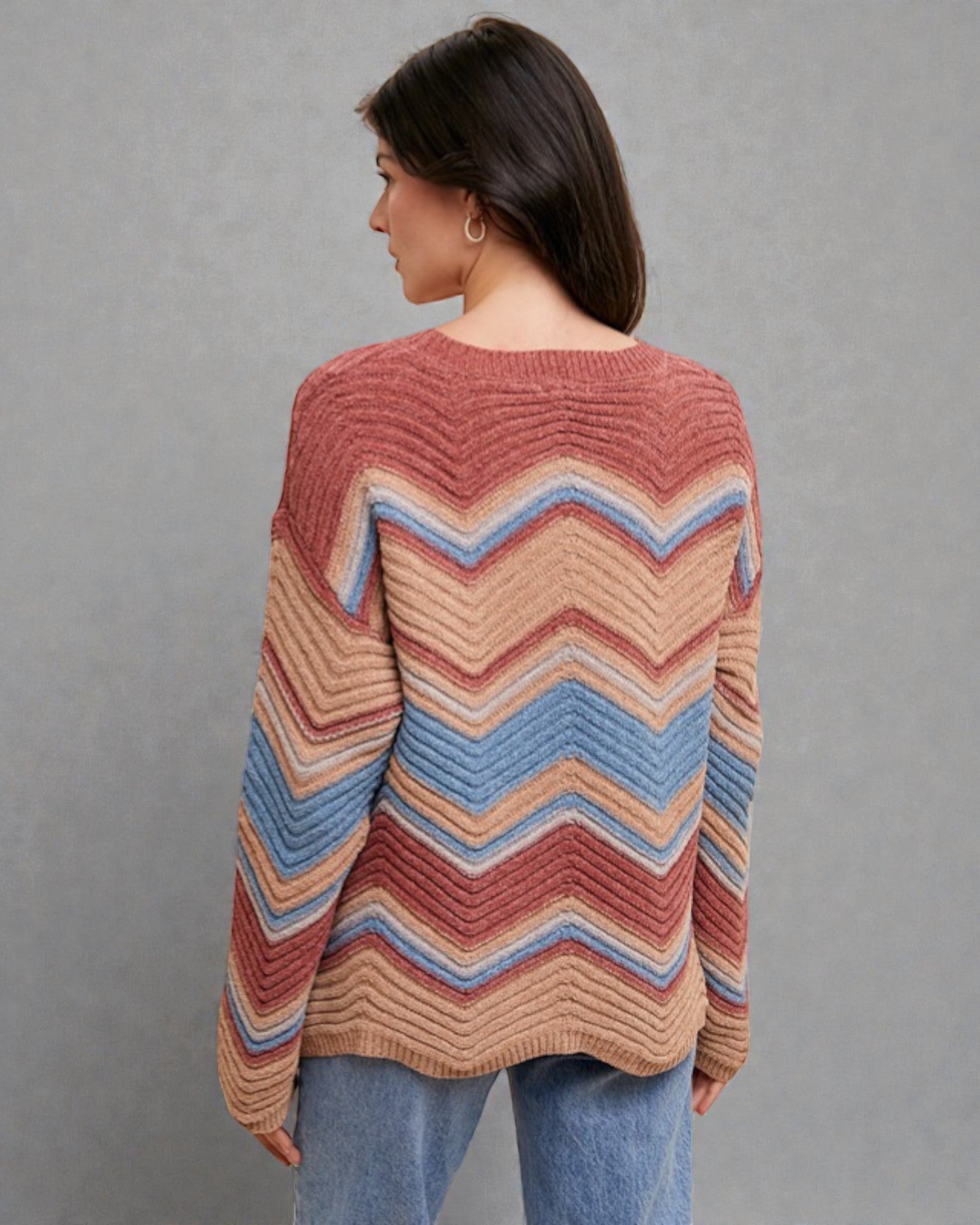 Woman wearing a colorful striped sweater against a gray background