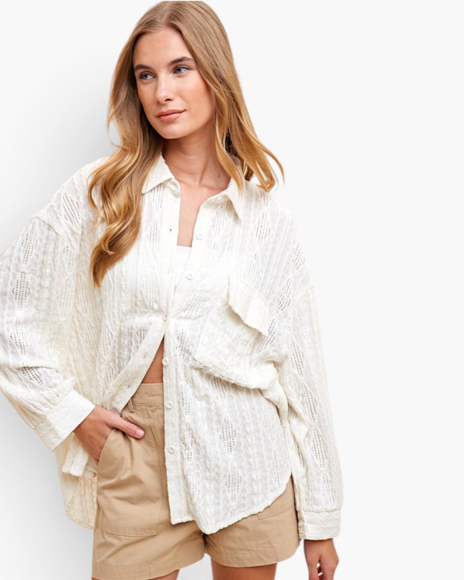 A woman wearing a textured off-white button-up shirt with ruffle details and beige shorts, photographed against a clean white studio background.