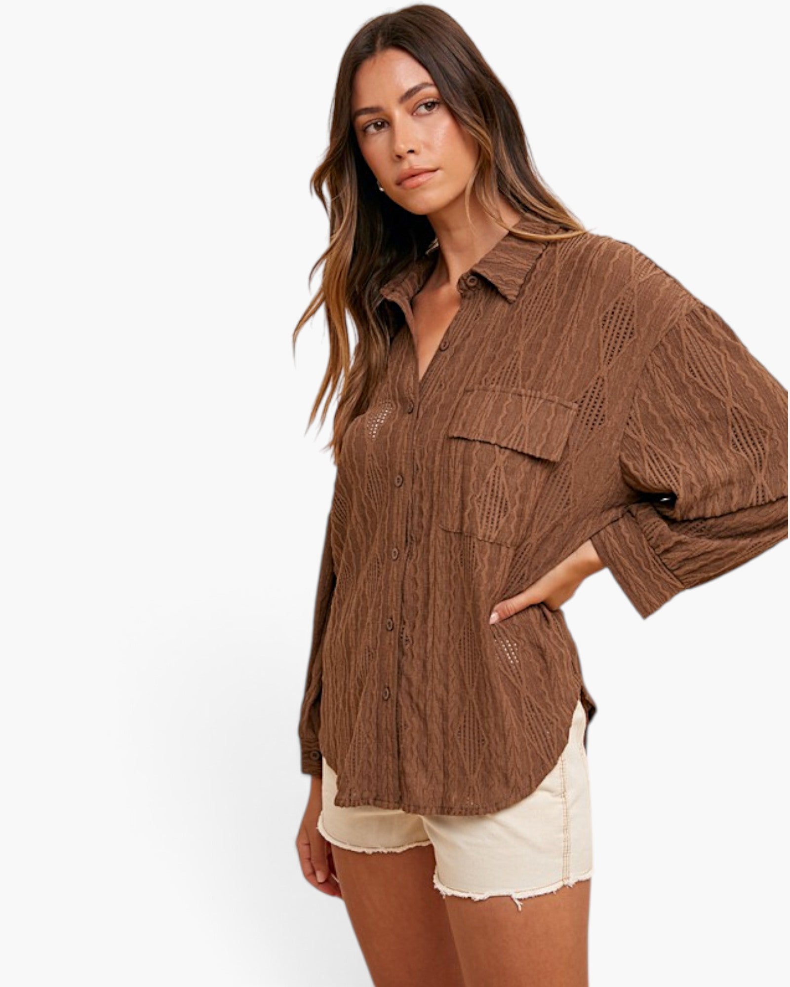 A woman modeling a brown textured button-up shirt with three-quarter sleeves and a chest pocket, paired with cream shorts, against a plain white background.